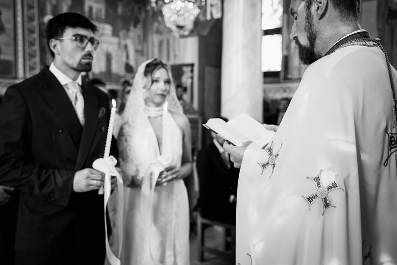 Младоженците със свещи, докато свещеникът чете, черно-бял кадър