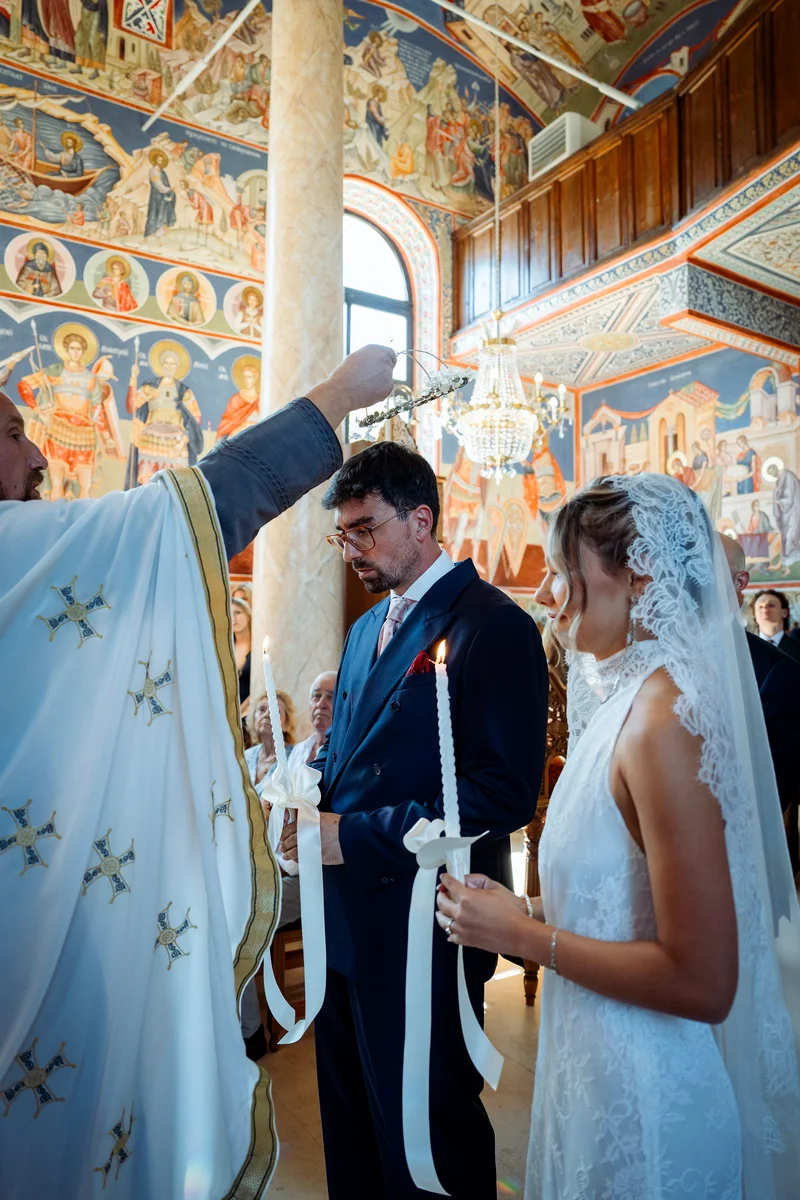 Венчавка в църква със стенописи: свещеникът благославя младоженците със свещи
